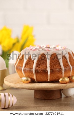 Delicious Easter cake decorated with sprinkles near eggs on wooden table
