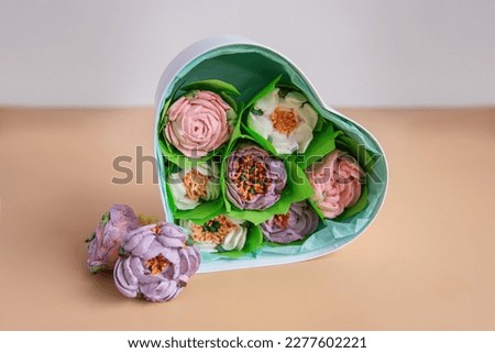On orange isolated background lies gift box heart shape with sweet marshmallow flowers. Hand natural work. Dessert without sugar dessert peonies roses aster. Hobby, small business. Mock up, copy space