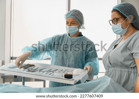 Doctor and nurse examining table with surgical instruments before the operation Royalty-Free Stock Photo #2277607409