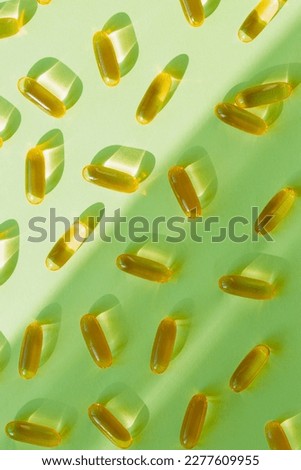 Pills of omega 3 close up on pastel green background with shadow. Health care concept. Supplements and vitamins. Top view. Flat lay. Selective focus