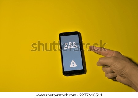 index finger of the hand indicating on the exclamation mark icon presence of problems on the smartphone screen yellow background copy space on the left