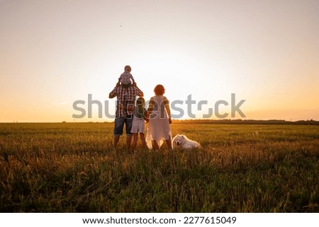 Silhouette of family with Samoyed dog at sunset. Faceless, people standing with backs to camera. The concept of travel, freedom, confidence in the future. Traveling with pets. Lifestyle childhood