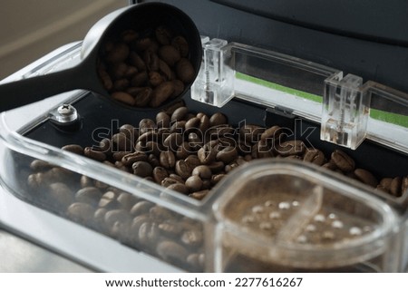 Coffee beans are poured into the grinding container of an automatic coffee maker machine, later the coffee in the container of this machine is automatically ground and accommodated in a cup for and re