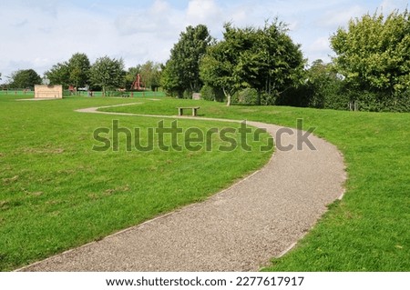 Scenic view of a winding stone path through a beautiful green park with leafy trees and a grass lawn