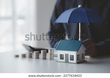 Individuals holding small umbrellas and model homes, housing insurance against impending loss and fire, building fire insurance, home and real estate insurance concepts. Royalty-Free Stock Photo #2277618423