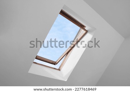 Open skylight roof window and lamps on slanted ceiling in attic room, low angle view Royalty-Free Stock Photo #2277618469