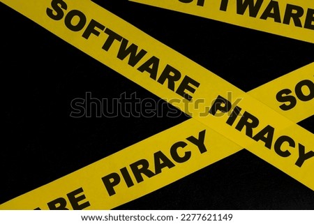 Software piracy alert, caution and warning concept. Yellow barricade tape with word in dark black background.