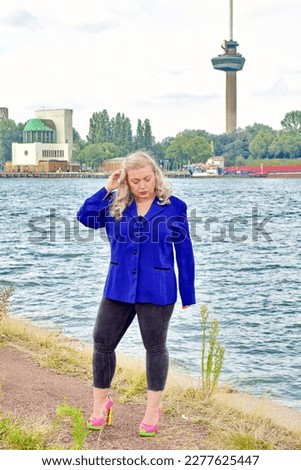 Blonde plus size model wearing blue jacket nature water background travelling travel posing in nature blog glamout fashion article