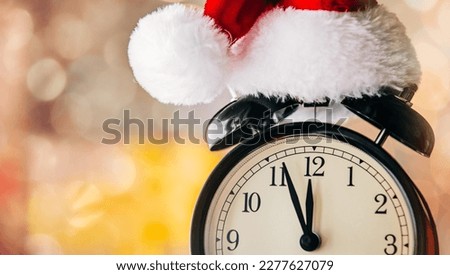 Vintage Alarm clock in Santa Claus hat with Christmas gift and Ligths on background