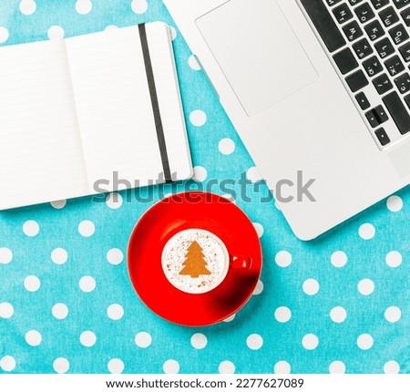 Cup of coffee and notebook near laptop comuter on blue polka dot background