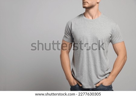 Man wearing blank t-shirt on light grey background, closeup. Mockup for design