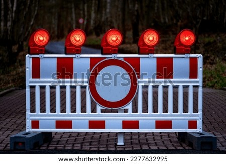 Traffic barring with red battery flash lights indicating road closure, “no entry“ or “do not pass“ at construction sites, accidents or blocked roads. Forest road closed for toad migration in Germany. Royalty-Free Stock Photo #2277632995