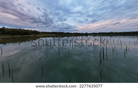 Forest trees silhouette reflection on the quiet lake surface, very peaceful, no people, dramatic sky reflection in the lake. High quality photo