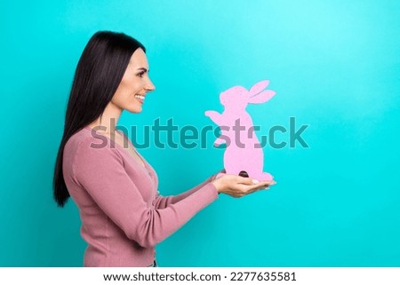 Side profile photo of cute girl straight hairdo pastel cardigan look empty space hold rabbit isolated on vibrant teal color background