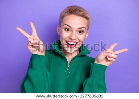 Photo of excited funky woman dressed green pullover showing two v-signs isolated purple color background