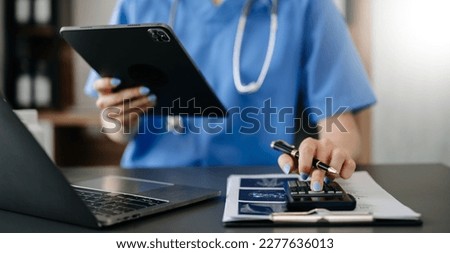 Healthcare costs and fees concept.Hand of smart doctor used a calculator and smartphone, tablet for medical costs at hospital 