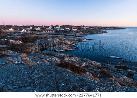 The picture displays a beautiful sunset over the harbor of an old Swedish seaside cabins, surrounded by stunning architecture.