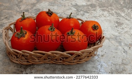 Fresh red tomatoes laid out in wicker basket on cement floor background. Closeup photo.