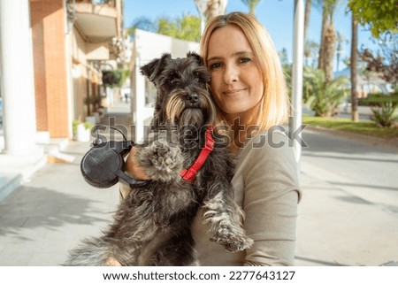 young woman and her cute puppy of schnauzer outdoors in the city