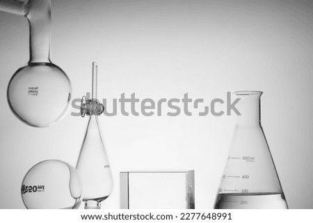 An erlenmeyer flask filled with water and scientific glassware. Transparent podium to show product. Research and development cosmetics concept. Royalty-Free Stock Photo #2277648991