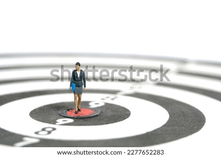 Miniature people toy figure photography. Career track concept. A businesswoman walking on dartboard. Isolated on white background. Image photo
