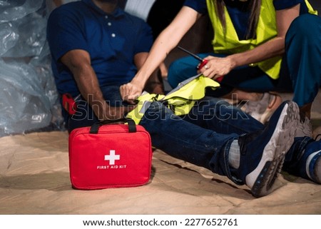 Emergency staff in safety suit help a man who has knee injuries from accident in factory workplace, First aid training in industrial company. Royalty-Free Stock Photo #2277652761