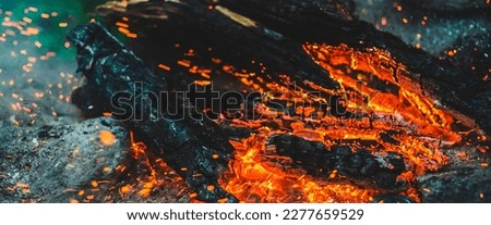 Vivid smoldered firewoods burned in fire close-up. Atmospheric background with orange flame of campfire. Full frame image of bonfire. Warm whirlwind of glowing embers and ashes in air. Sparks in bokeh Royalty-Free Stock Photo #2277659529