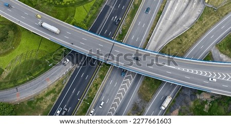 Aerial top view of highway junction interchange road. Drone view of the elevated road, traffic junctions, and green garden. Transport trucks and cars driving on highway. Infrastructure in modern city. Royalty-Free Stock Photo #2277661603