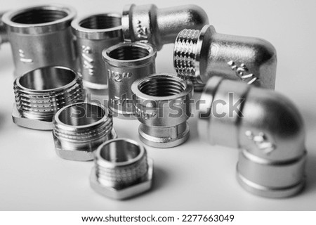Black and white photo. Close up of plumbing fittings and details of brass metal water tees isolated on light background