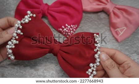 Handmade hair bow in beautiful maroon color embellished with pearls and rhinestones. A great hair clip accessory for girls and women. Royalty-Free Stock Photo #2277668943