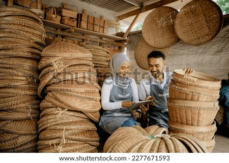 asian muslim woman and her partner checking bamboo product at their traditional workshop