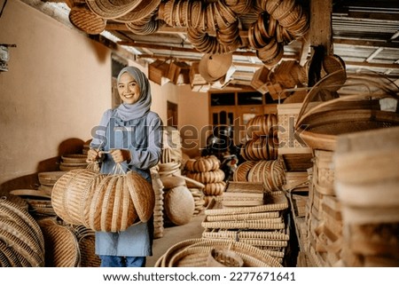 proud seller holding her bamboo craft product and smiling to camera Royalty-Free Stock Photo #2277671641