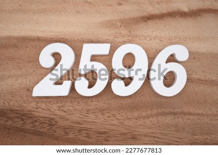 White number 2596 on a brown and light brown wooden background.
