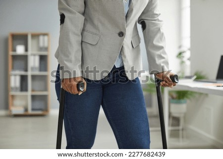 Corporate employee walking with crutches at work. Cropped shot of an unrecognizable young disabled African American woman with crutches standing in the office. Injury, disability and work concept