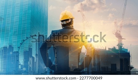 Engineer wearing yellow helmet for workers security  of new highrise apartment buildings and construction cranes on evening sunset. Bussiness, Engineer and architect concepts.