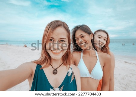 3 best friends taking selfies together while at a beautiful beach. Tourists posting a picture of them together on social media.