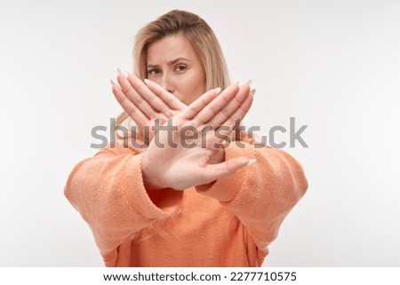 Portrait of young blonde woman showing stop sign with hand isolated on white background
