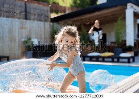 Happy kid having fun when running round the swimming pool with. Summer outdoor water activity for kids.