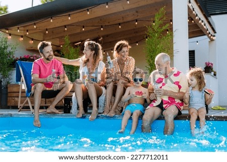 Multi generation family enjoying summer time, sitting at backyard pool. Royalty-Free Stock Photo #2277712011