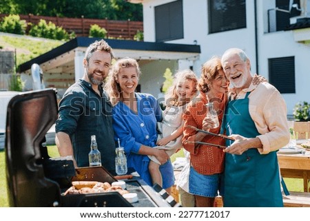 Multi generation family grilling outside on backyard in summer during garden party Royalty-Free Stock Photo #2277712017