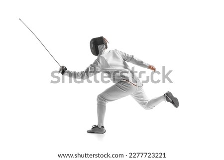 Dynamic portrait of male athlete in fencing costume with sword in hand in action isolated on white studio background. Concept of sport, competition, professional skills, achievements. Royalty-Free Stock Photo #2277723221