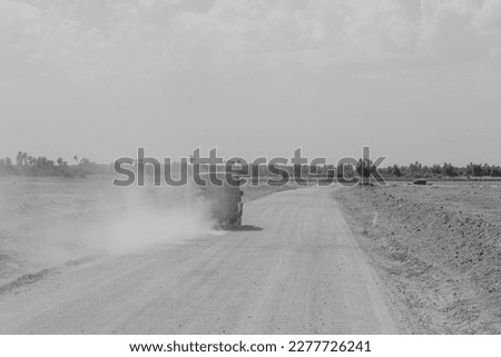 Game drive on dirt road with safari car in national park in beautiful landscape scenery with dust raised from driving car, Africa, black and white photography