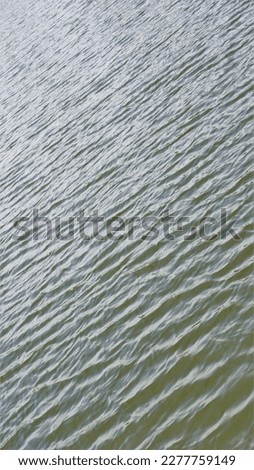 Beautiful natural wave pattern of water with reflection of bright sun light on sunny day. Abstract texture background image.