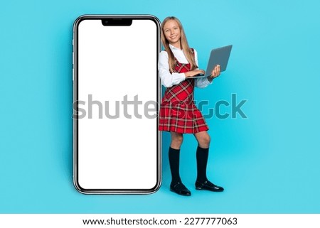 Full body photo of cheerful schoolgirl hold wireless netbook empty space electronic ui menu isolated on blue color background