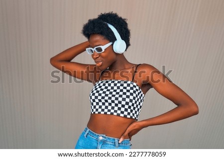 Stylish african american woman listening to music in headphones on the street.