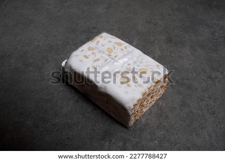 Photo of raw tempeh wrapped in plastic on a dark background