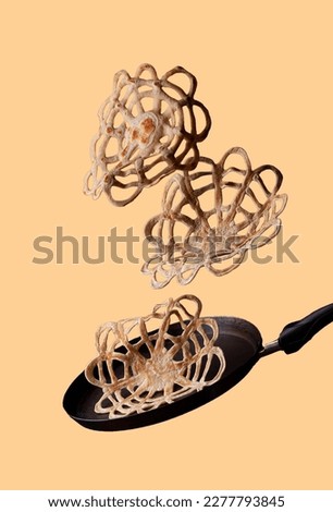lace pancakes fly over a frying pan on a yellow background