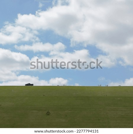 Local Park in the heartland of America looking up a hill at lone truck on top across field beautiful day sky and clouds wide angle landscape-photography.