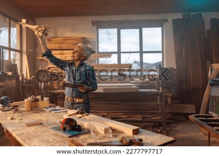 A female mid adult Caucasian carpenter is in her workshop testing out a wooden toy design. Royalty-Free Stock Photo #2277797717