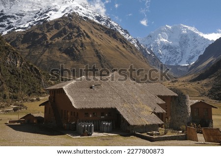 Yellow house overlooking the sacred Salkantay mountain on a beautiful winter day with blue sky